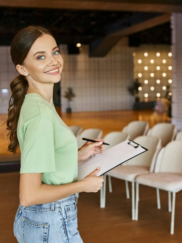 pleased-event-organizer-with-clipboard-smiling-at-camera-in-modern-banquet-hall-creative-work.jpg